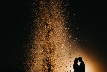 Noivos se Beijando com Luzes ao Fundo em Casamento